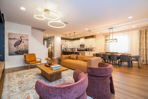 Ein modernes Wohnzimmer mit einer Couch, Sesseln, einem Couchtisch und einem Gemälde an der Wand.