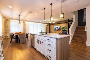 A modern kitchen with a central island, wooden flooring, and pendant lighting. - Stupendous Disney Vacation Home W Private Pool (Kissimmee)
