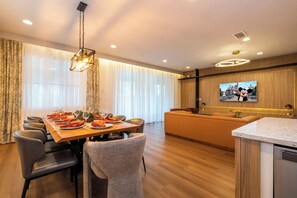 A modern hotel room with a dining area, a sofa, and a television displaying a cartoon character. - Stupendous Disney Vacation Home W Private Pool (Kissimmee)