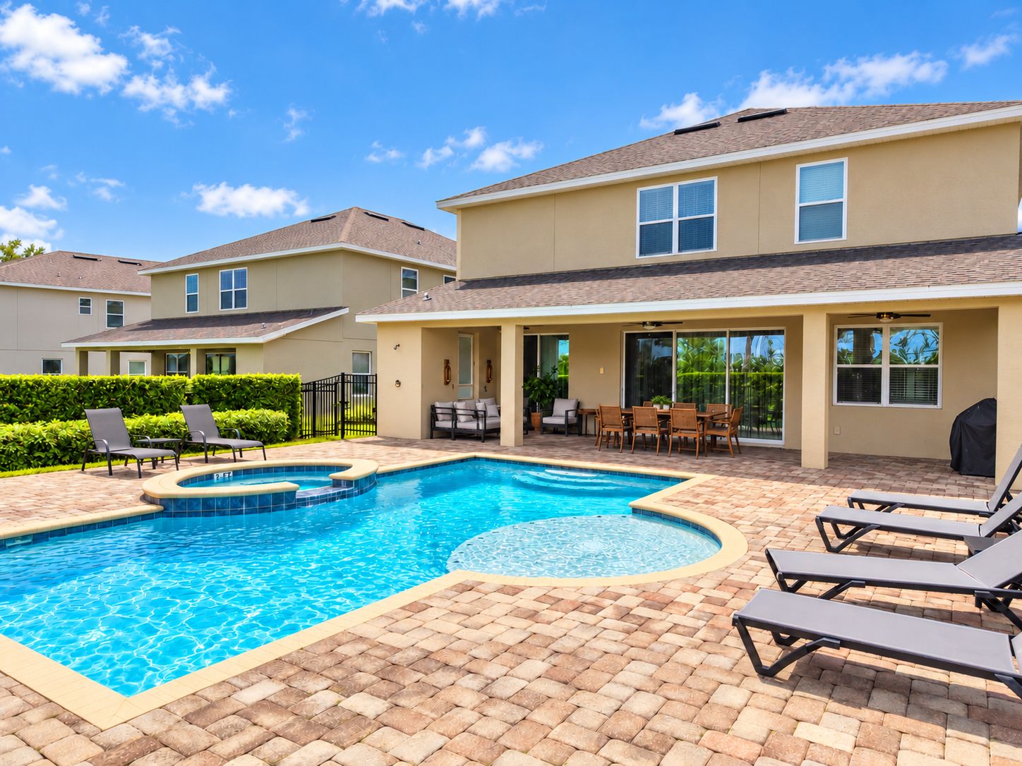 A residential property with a swimming pool, outdoor seating, and a covered patio area.
