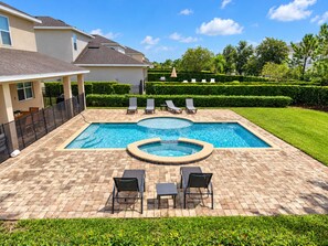 A rectangular swimming pool with a hot tub, surrounded by a brick patio, lounge chairs, and a well-maintained lawn. - Stupendous Disney Vacation Home W Private Pool (Kissimmee)
