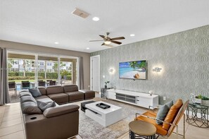 Un salon moderne avec un canapé, une table basse, un téléviseur et un balcon offrant une vue agréable.