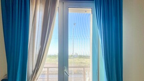 A room with a sliding glass door, curtains, and a view of a balcony with a railing. - Blue Room - Double Room with Private Garage (Bitonto)