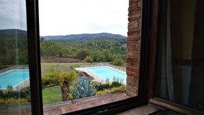 A view through a window of a swimming pool surrounded by greenery and hills. - Wonderful private villa with private pool, hot tub, WIFI, TV, pets allowed and panoramic view (Monte Castello Di Vibio)