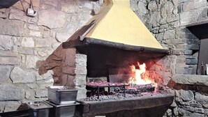 A stone fireplace with a yellow chimney, burning wood, and a metal container on the hearth. - Wonderful private villa with private pool, hot tub, WIFI, TV, pets allowed and panoramic view (Monte Castello Di Vibio)