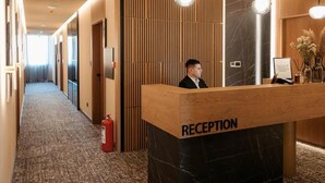 A reception desk with a 'RECEPTION' sign, a fire extinguisher, and a wooden panel wall. - TRADICIJA HOTEL (Banja Luka)