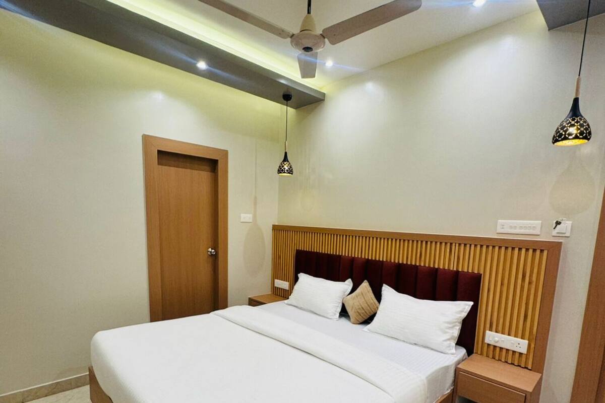 Un dormitorio moderno con una cama grande, ventilador de techo, lámparas de noche y cabecero de madera.