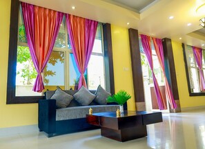 A modern hotel lobby with a sofa, a coffee table, and colorful curtains. - DJ Palace Puri (Puri)