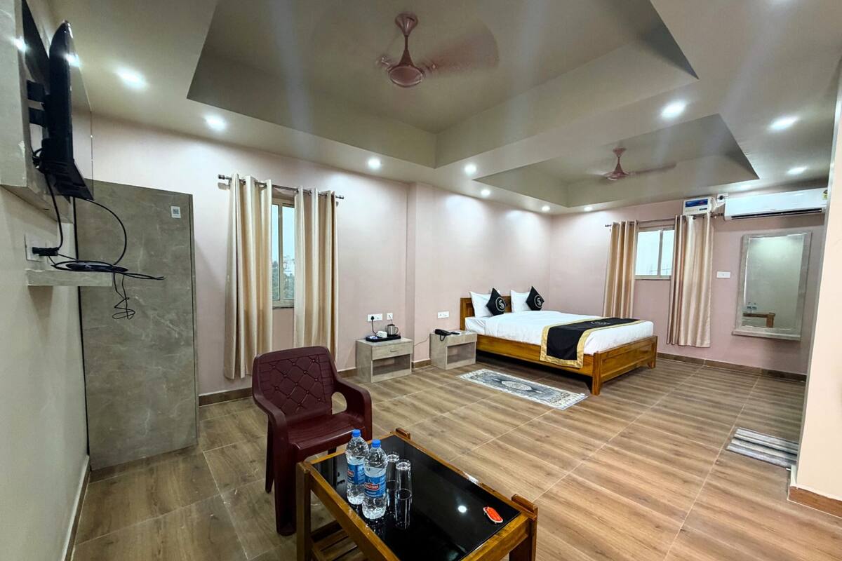 Habitación de hotel con cama, escritorio con silla, televisor montado en la pared y equipo de aire acondicionado.