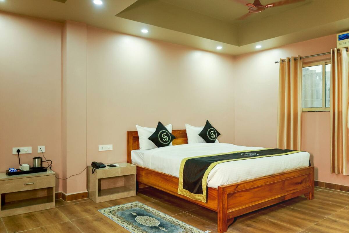 Un dormitorio con cama de madera, mesitas de noche, un escritorio y una ventana con cortinas.