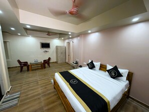 Una habitación de hotel con cama, escritorio, silla, televisor y armario.