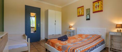 A bedroom with a bed, a wardrobe, a desk, and a chair.