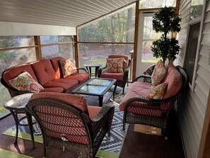 A covered patio with wicker furniture, a glass coffee table, and a view of a wooded area. - 3BR/2BA Ocean Pines Home w/ Screened Porch & Deck Near Pools, Golf & Yacht Club! NEW LISTING! (Ocean Pines)