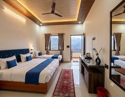 A hotel room with a large bed, a desk, a mirror, and a view of mountains.