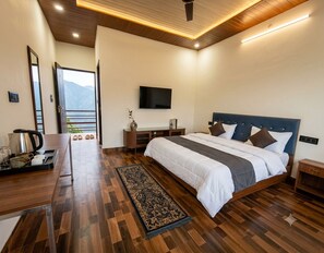 Ein modernes Schlafzimmer mit einem großen Bett, Holzboden, einem Flachbildfernseher und Blick auf Berge.