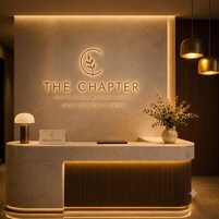 A reception desk with a sign reading 'THE CHAPTER' and a slogan 'EVERY STAY TELLS A STORY'.