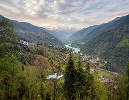 A valley with a river, mountains, and a small settlement.