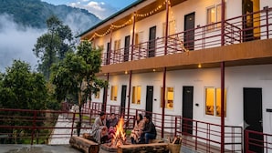 A two-story building with balconies, a fire pit, and a view of a forested mountain.