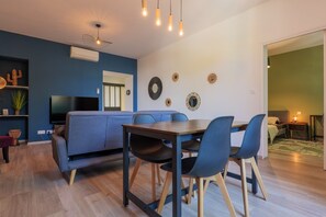Una sala de estar moderna con sofá, mesa de comedor, sillas y televisor.