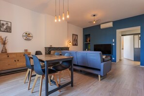 A modern living room with a dining area, a sofa, and a TV.