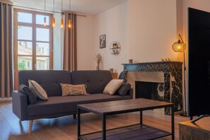 A living room with a sofa, a coffee table, a fireplace, and a TV.