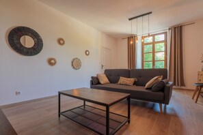 A living room with a sofa, a coffee table, and decorative wall art. - Cosy T4 Apartment in City Center with Wi-Fi and Air Conditioning (Aubenas)