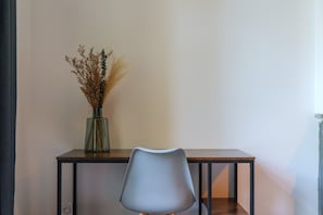 A chair and a table with a vase of dried plants.