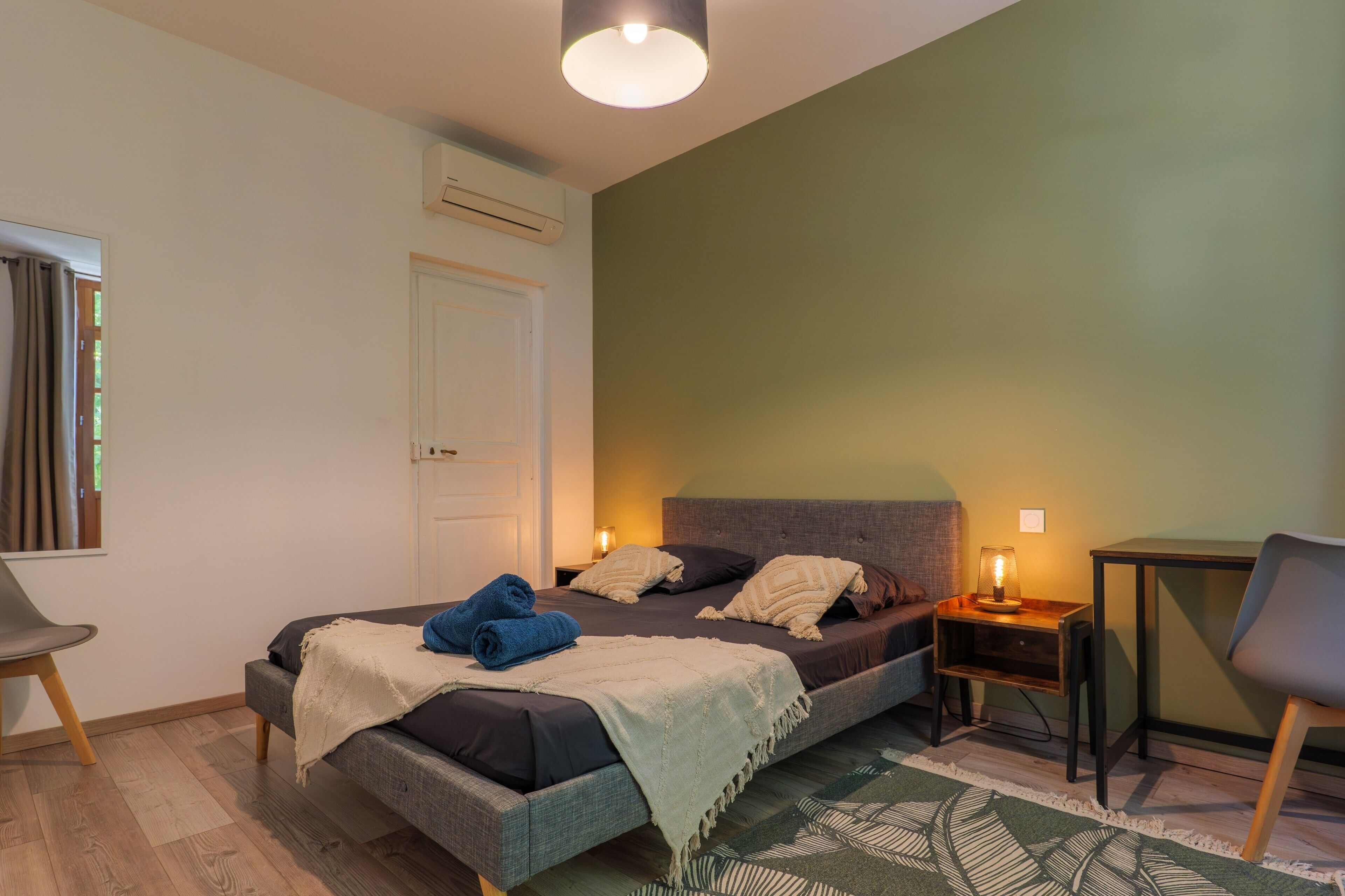 Een slaapkamer met een bed, nachtkastjes, een stoel en een bureau.
