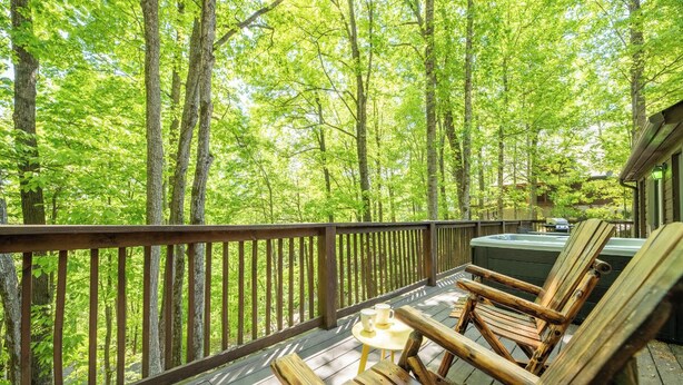 Une terrasse en bois avec un jacuzzi, des chaises longues et une table avec des tasses.