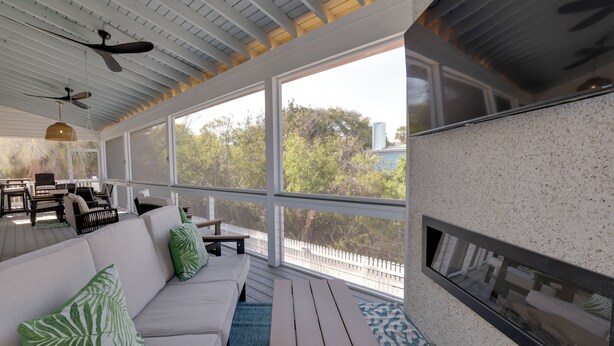 A sunlit room with a white sofa, green pillows, a ceiling fan, and a view of trees and buildings outside. - Palmwood Haven | Private Pool, 2nd House From Sand! (Tybee Island)