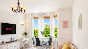 Un salon équipé d’un téléviseur, d’un canapé, d’une table basse et offrant une vue sur la verdure environnante.