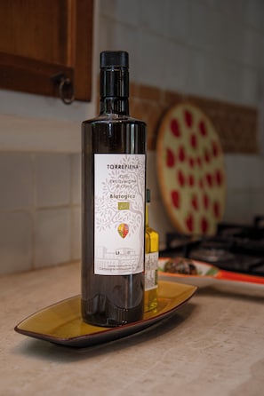 A bottle of Torrepiena olive oil on a yellow plate in a kitchen.