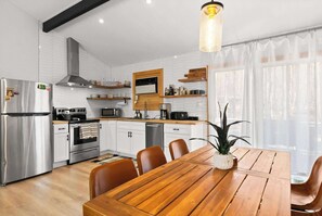 Eine moderne Küche mit Edelstahlgeräten, einem Holzespeisetisch und einem großen Fenster mit durchsichtigen Vorhängen.