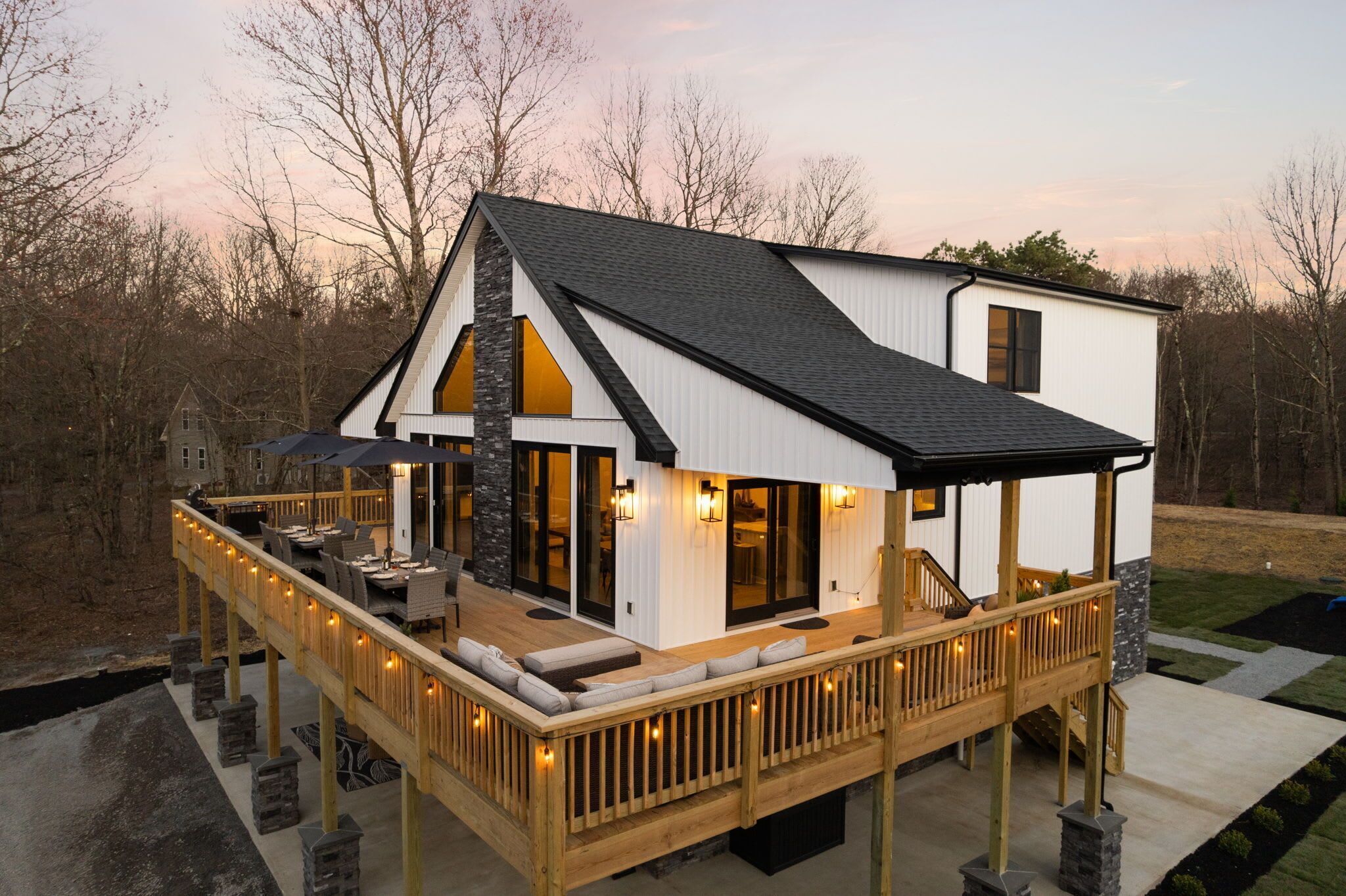 A modern house with a deck, large windows, and a stone exterior.