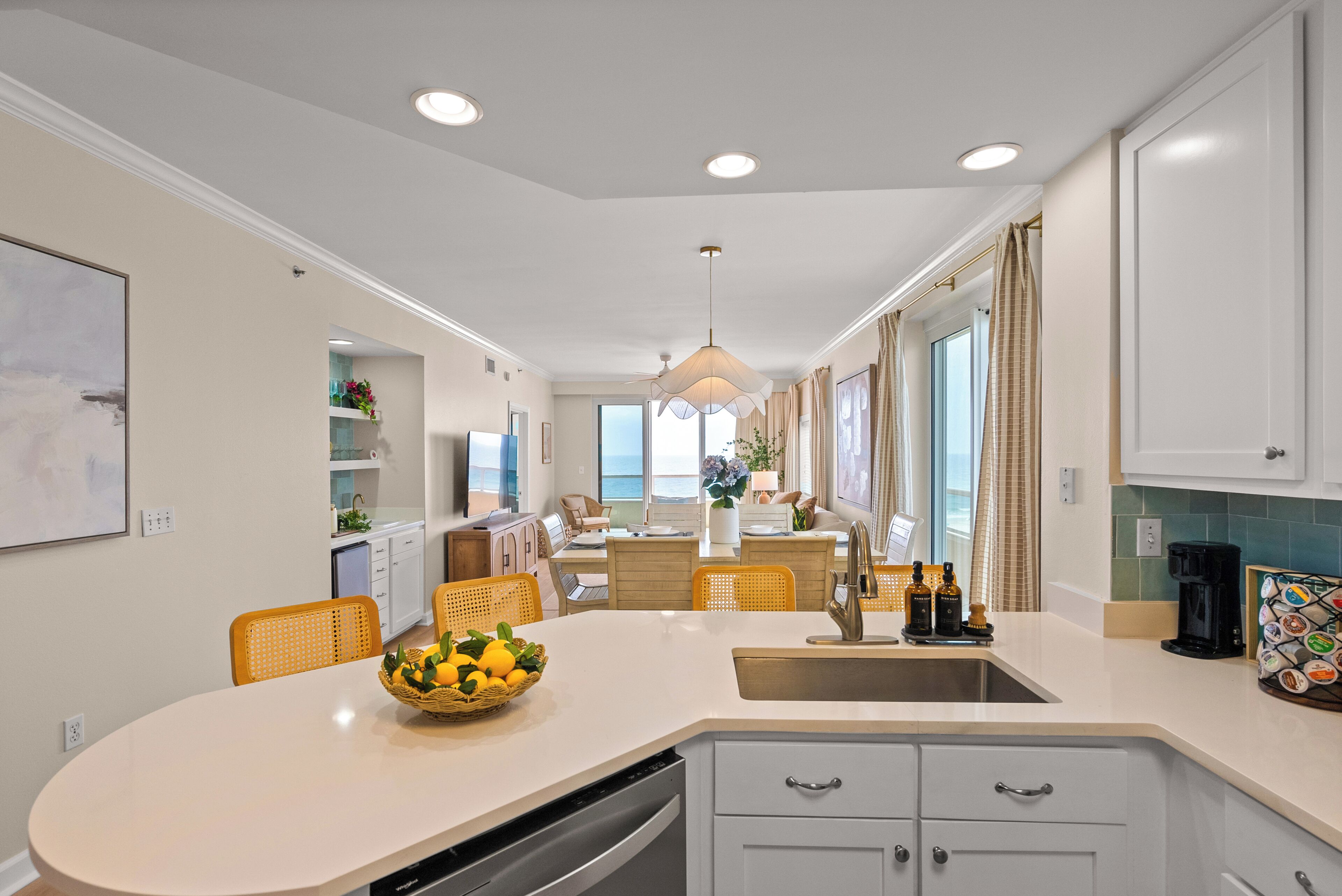 Een moderne keuken met een centraal eiland, inbouwapparatuur en een eetgedeelte met stoelen.