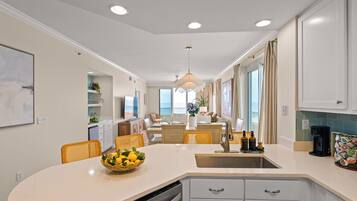 Een moderne keuken met een centraal eiland, inbouwapparatuur en een eetgedeelte met stoelen.