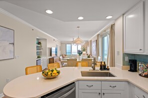 Een moderne keuken met een centraal eiland, inbouwapparatuur en een eetgedeelte met stoelen.