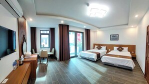 Ein Hotelzimmer mit zwei Betten, einem Schreibtisch, einem Stuhl, einem Fernseher und einem Fenster mit Vorhängen.