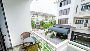 Ein Balkon mit Korbstühlen, einem Tisch und Blumentöpfen.
