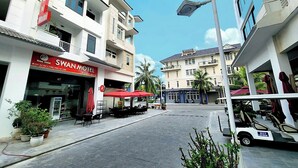 Straßenansicht mit einem SWAN MOTEL, Außenbereich mit Sitzgelegenheiten und einem Golfwagen.
