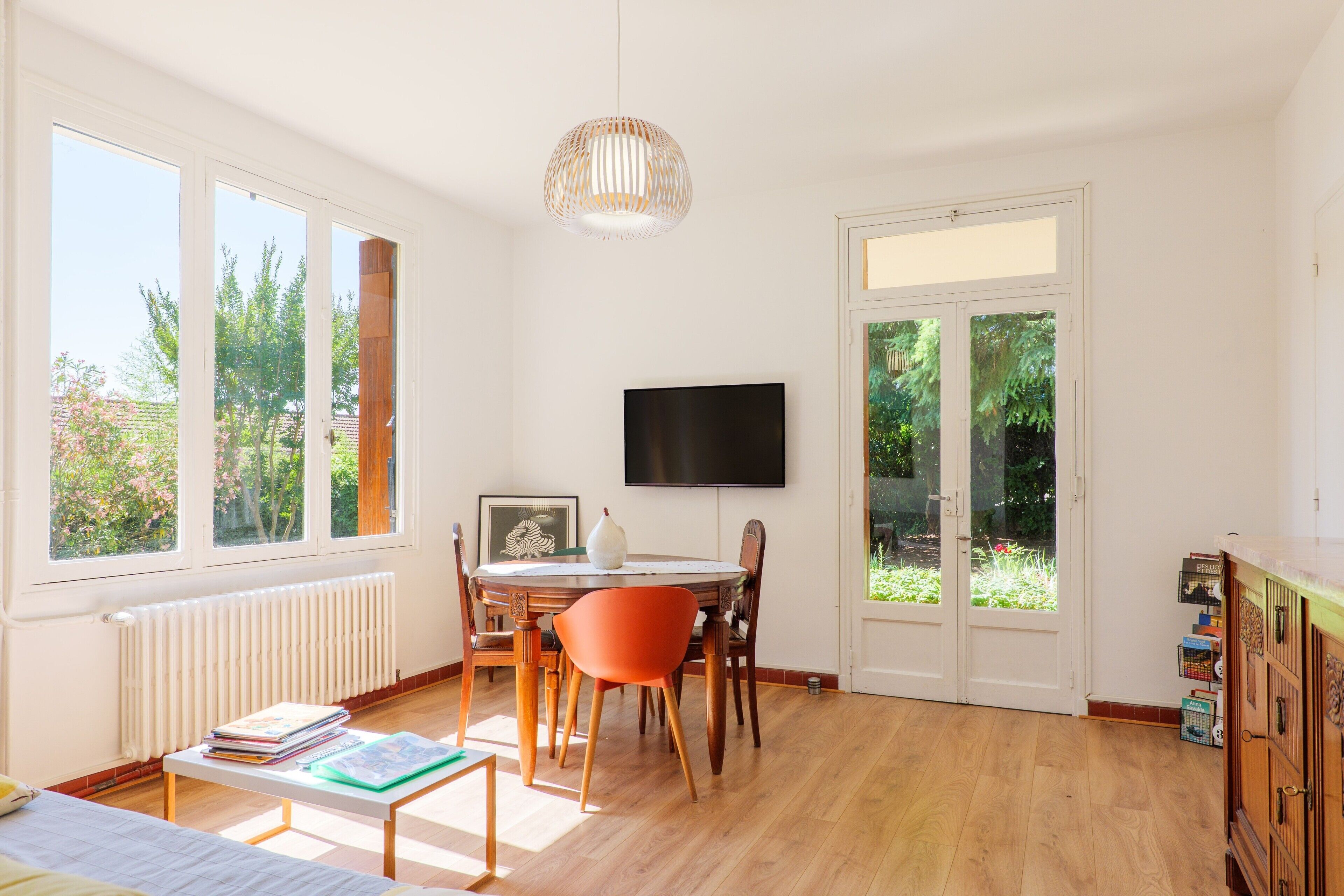 Une pièce comprenant une table à manger, des chaises, un téléviseur et de grandes fenêtres.