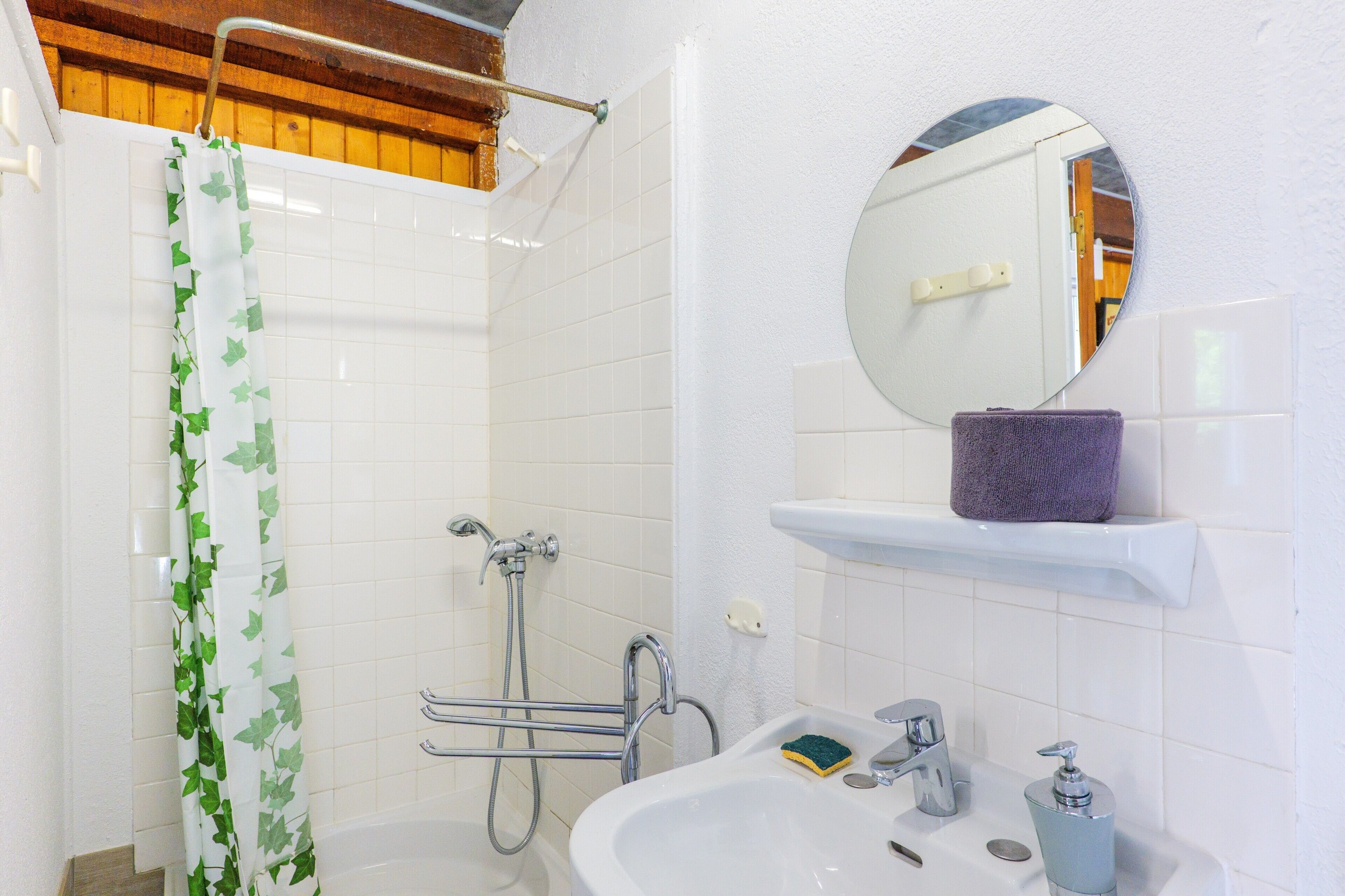 Une salle de bain équipée d’une douche, d’un lavabo, d’un miroir et d’un porte-serviettes.