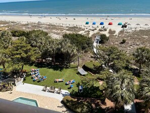 A beach view with a pool, lounge chairs, and umbrellas. - Oceanfront Couple’s Hideaway on the “Golden Mile” (Myrtle Beach)