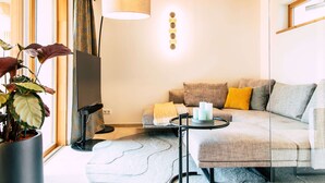 A modern living room with a sofa, a flat-screen TV, a lamp, and a potted plant. - Klochberg R&L APP Sunrise - Gelber Muskateller (Kloech)