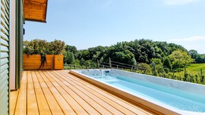 A wooden deck with a hot tub and a wooden planter with greenery. - Klochberg R&L APP Sunrise - Gelber Muskateller (Kloech)