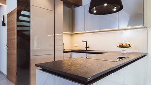 A modern kitchen with a central island, built-in cabinets, and a pendant light. - Klochberg R&L APP Sunrise - Gelber Muskateller (Kloech)