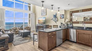 A modern kitchen with a large island, wooden cabinets, and a view of the ocean. - Two-Story penthouse with stunning Gulf views (Miramar Beach)