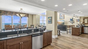 A spacious kitchen with a large island, wooden cabinets, and a view of the ocean. - Two-Story penthouse with stunning Gulf views (Miramar Beach)