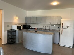 A kitchen with grey cabinets, a white refrigerator, a microwave, and a sink. - Fouka North Coast CL2-CH19-G01 (Marsa Matrouh)