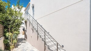 Uma escadaria de pedra estreita que sobe até um edifício branco com guarda-corpo de metal.